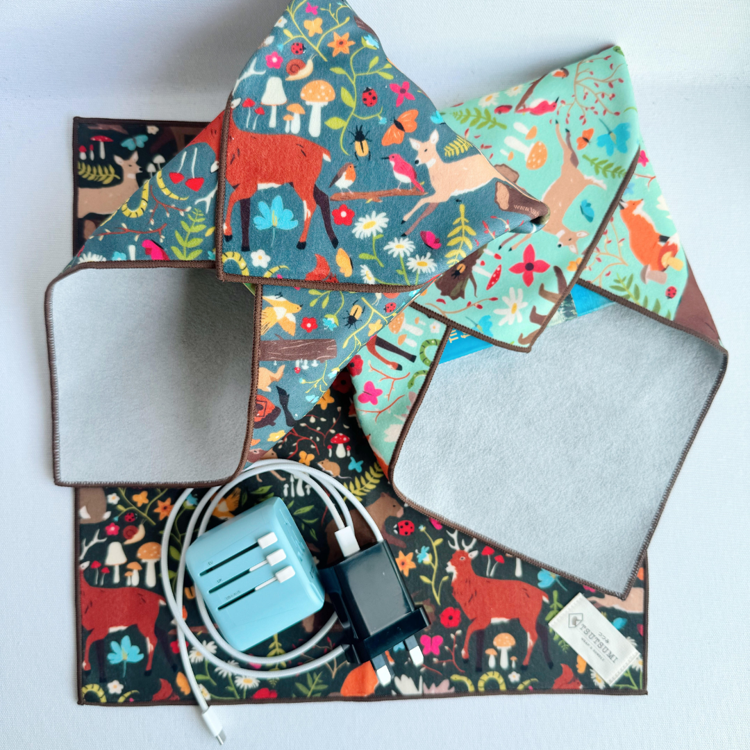2 packages wrapped with clingy wrap with Woodland Fantasy print in different colours, and cable and adaptor on top of a square piece of clingy wrap.