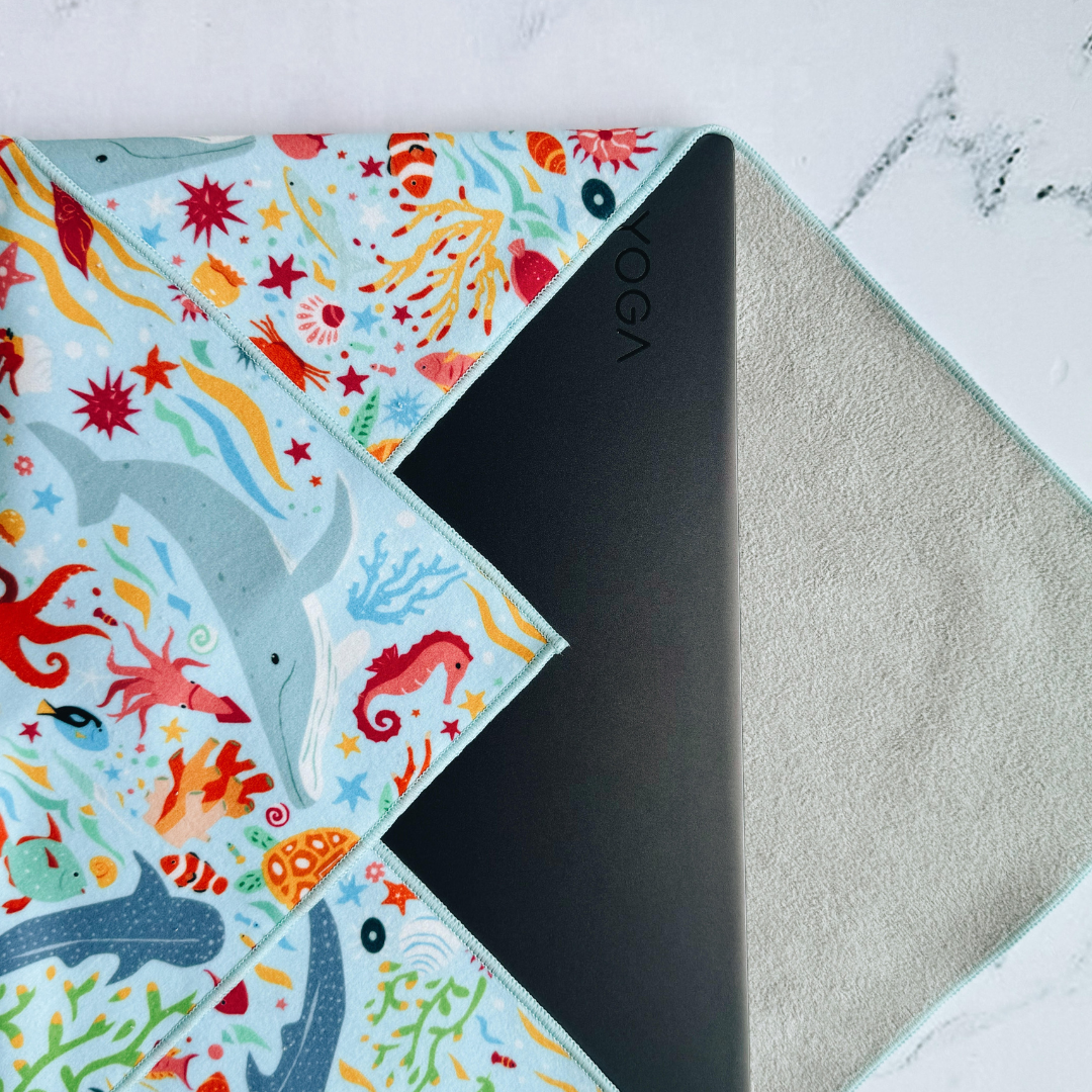 Tsutsumi Clingy Wrap with marine creatures artwork on light blue background, wrapping a laptop.