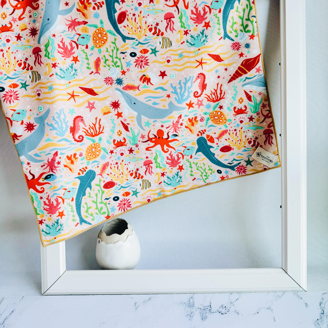 Tsutsumi Clingy Wrap with marine creatures artwork on light pink background, draped over a picture frame.