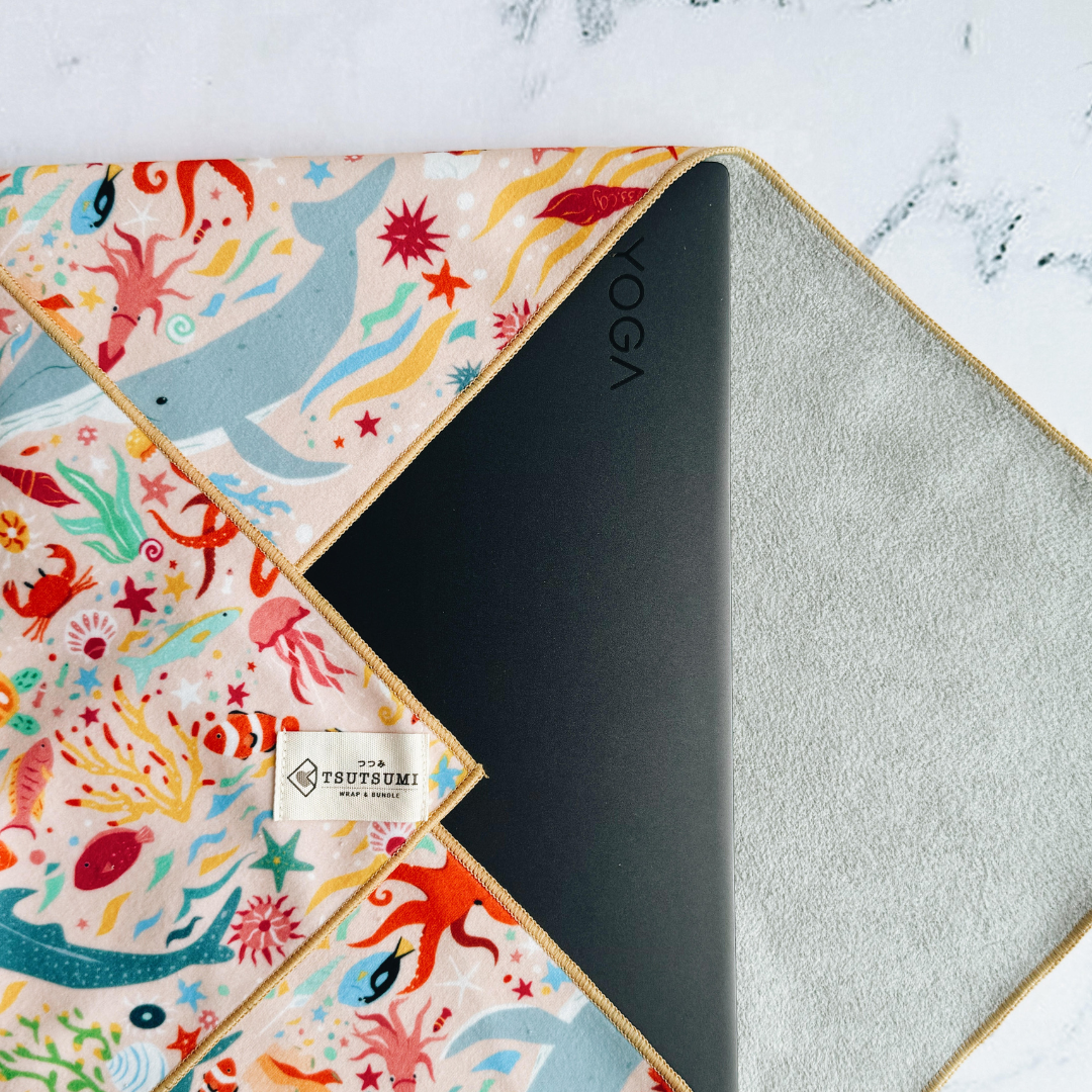 Tsutsumi Clingy Wrap with marine creatures artwork on light pink background, used to wrap a laptop.