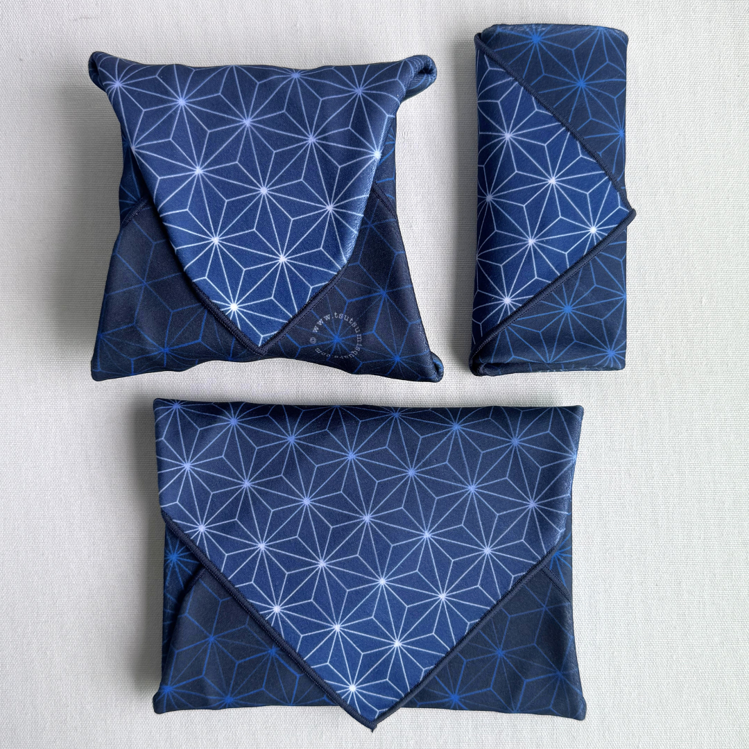 Three packages of different sizes wrapped using fabric with geometric pattern in blue
