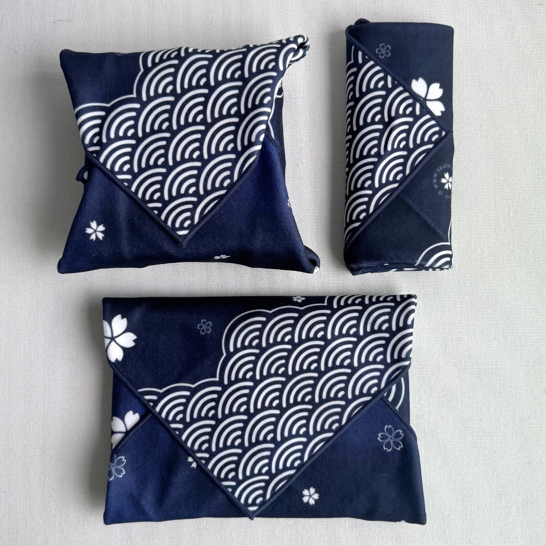 Three packages of different sizes wrapped using fabric with white sakura and seigaiha (wave) pattern in blue