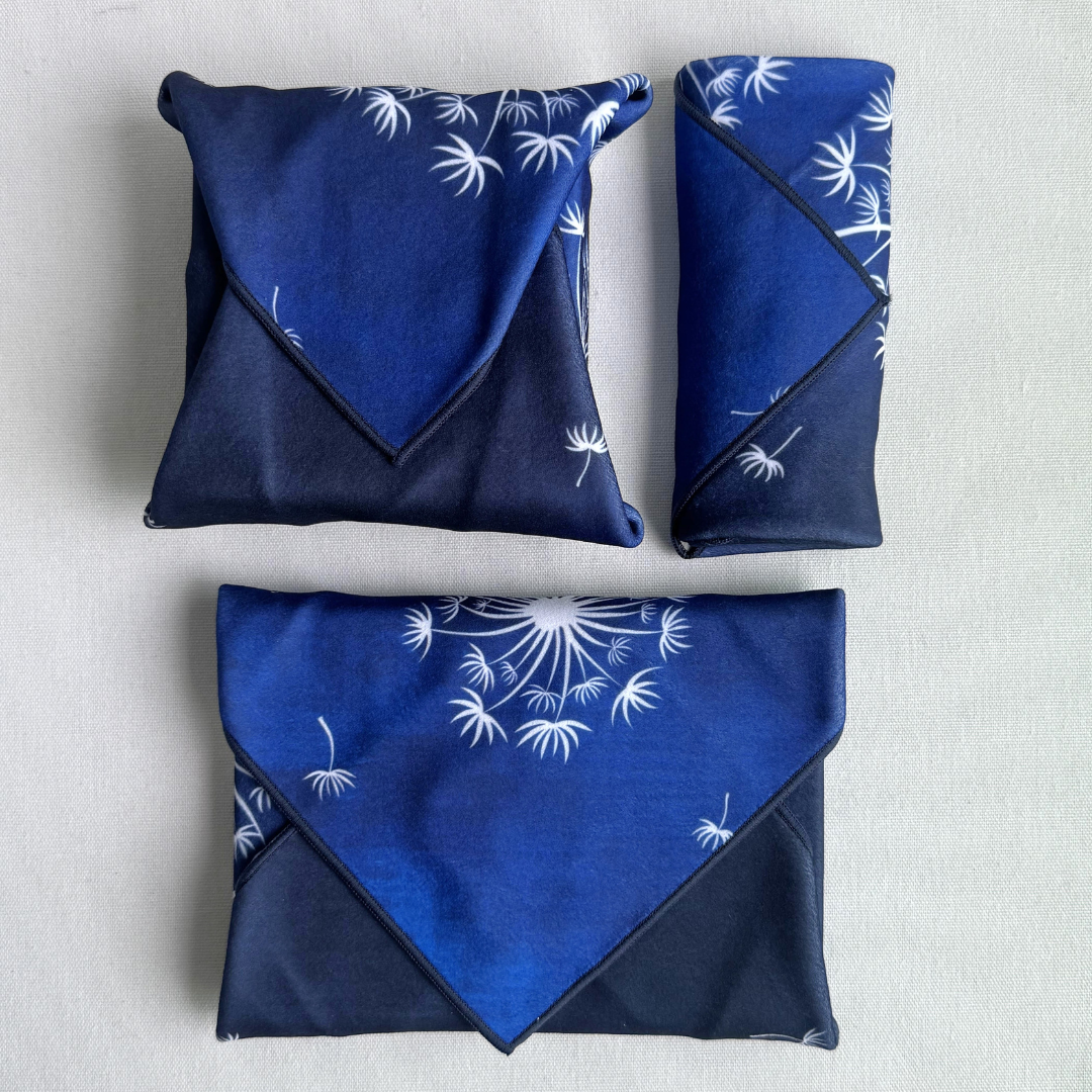 Three packages of different sizes wrapped using dark blue fabric with white dandelion pattern