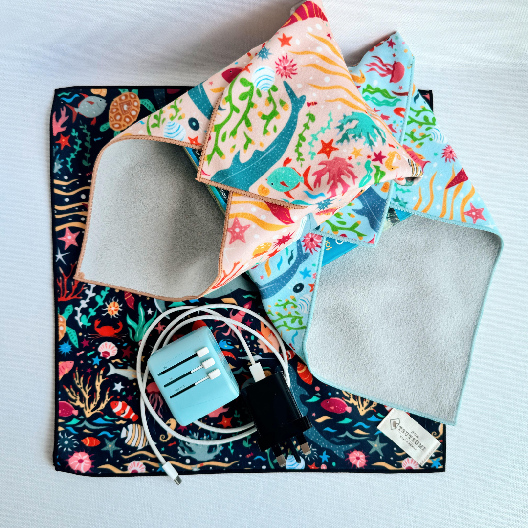 2 packages wrapped with clingy wrap with Marine Fantasy print in different colours, and cable and adaptor on top of a square piece of clingy wrap.