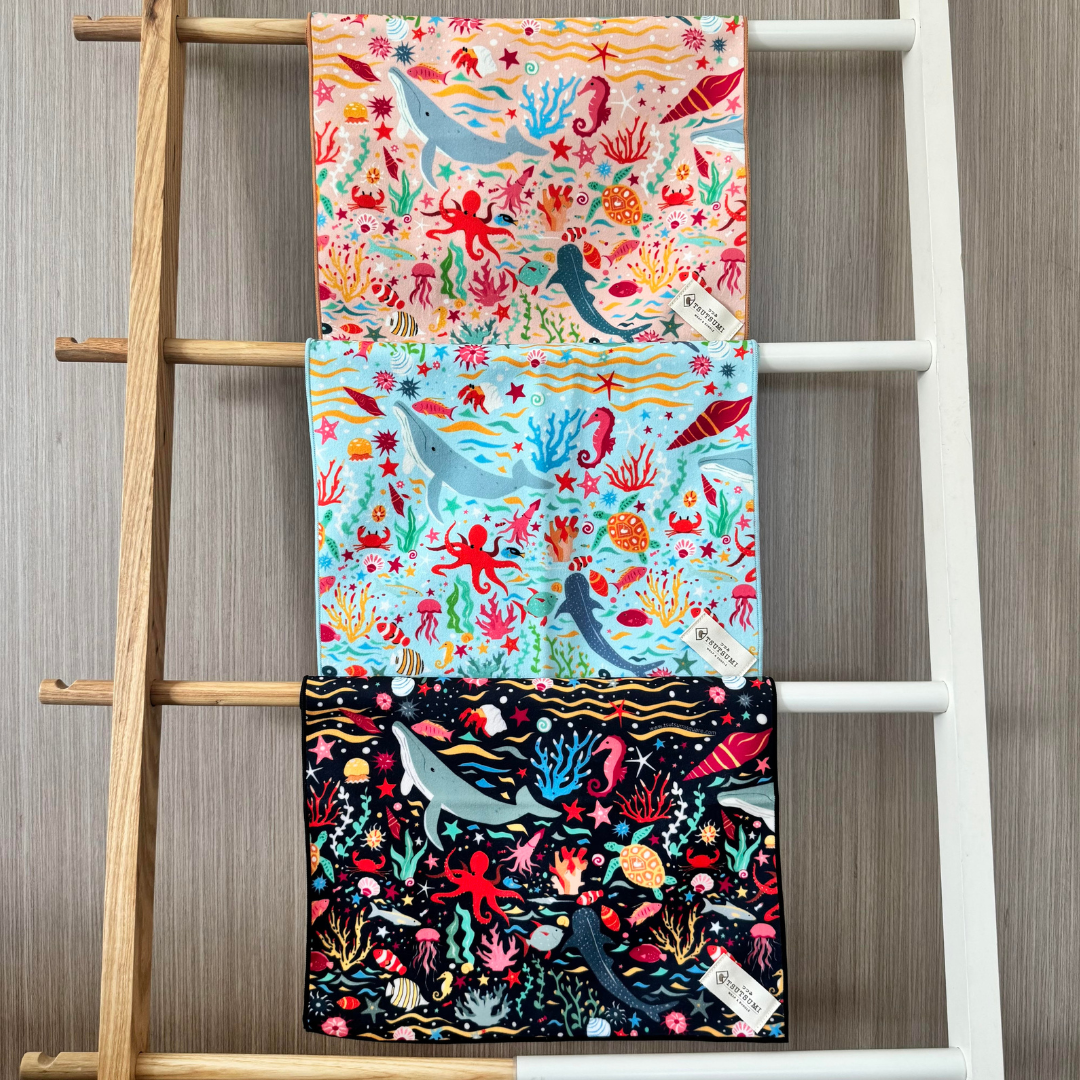 Set of three colorful animal-patterned clingy wraps displayed on a wooden ladder against a wooden wall.