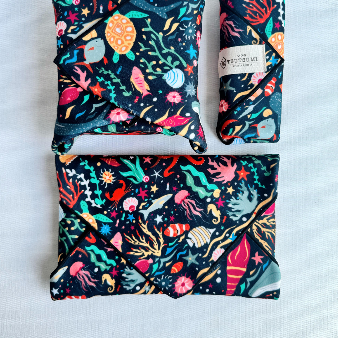 3 packages wrapped with fabric with Marine Fantasy print in dark blue background.