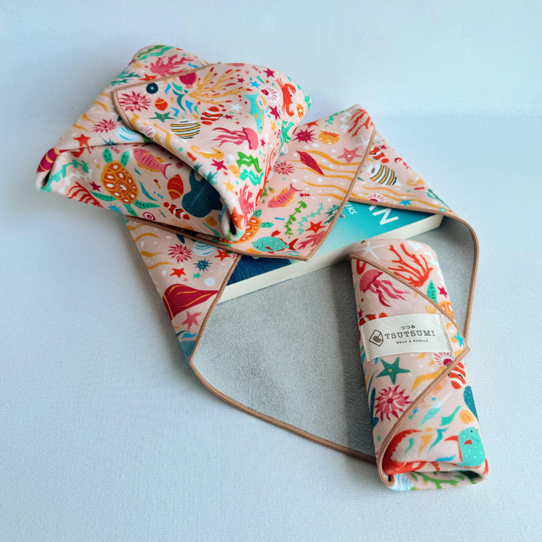 3 pieces of fabric with Marine Fantasy print in light pink background each wrapping different items.