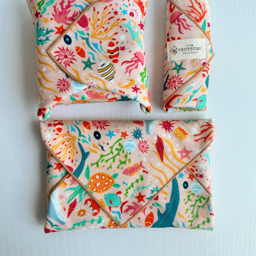 3 packages wrapped with fabric with Marine Fantasy print in light pink background