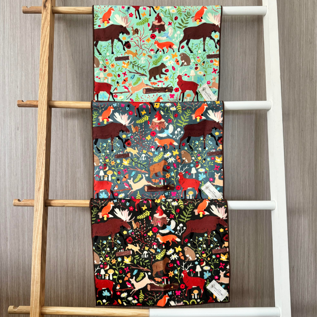 Set of three colorful animal-patterned clingy wraps displayed on a wooden ladder against a wooden wall.