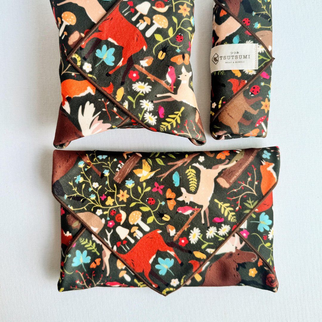 3 packages wrapped with fabric with Woodland Fantasy print in dark green background.