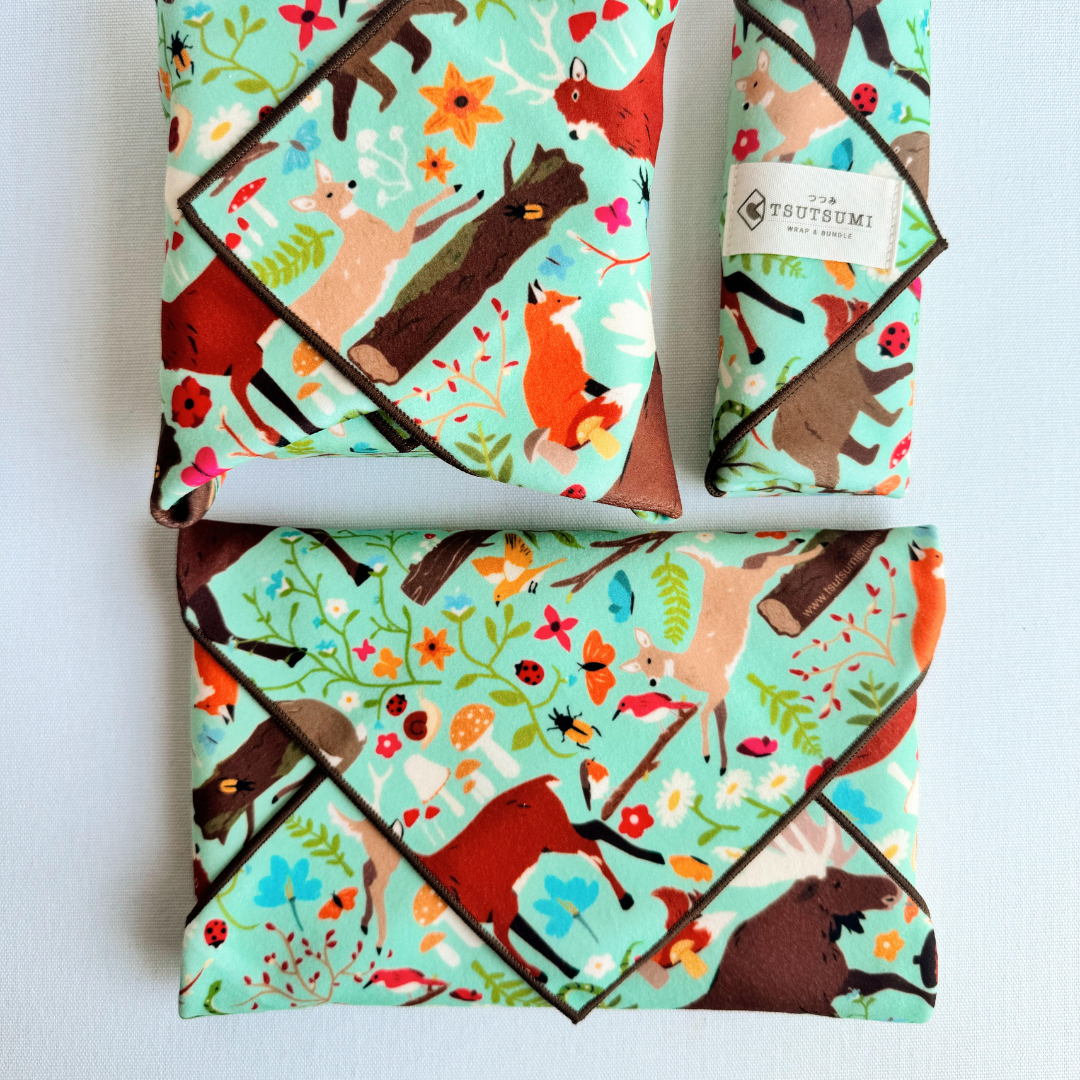 3 packages wrapped with fabric with Woodland Fantasy print in mint green 
background.