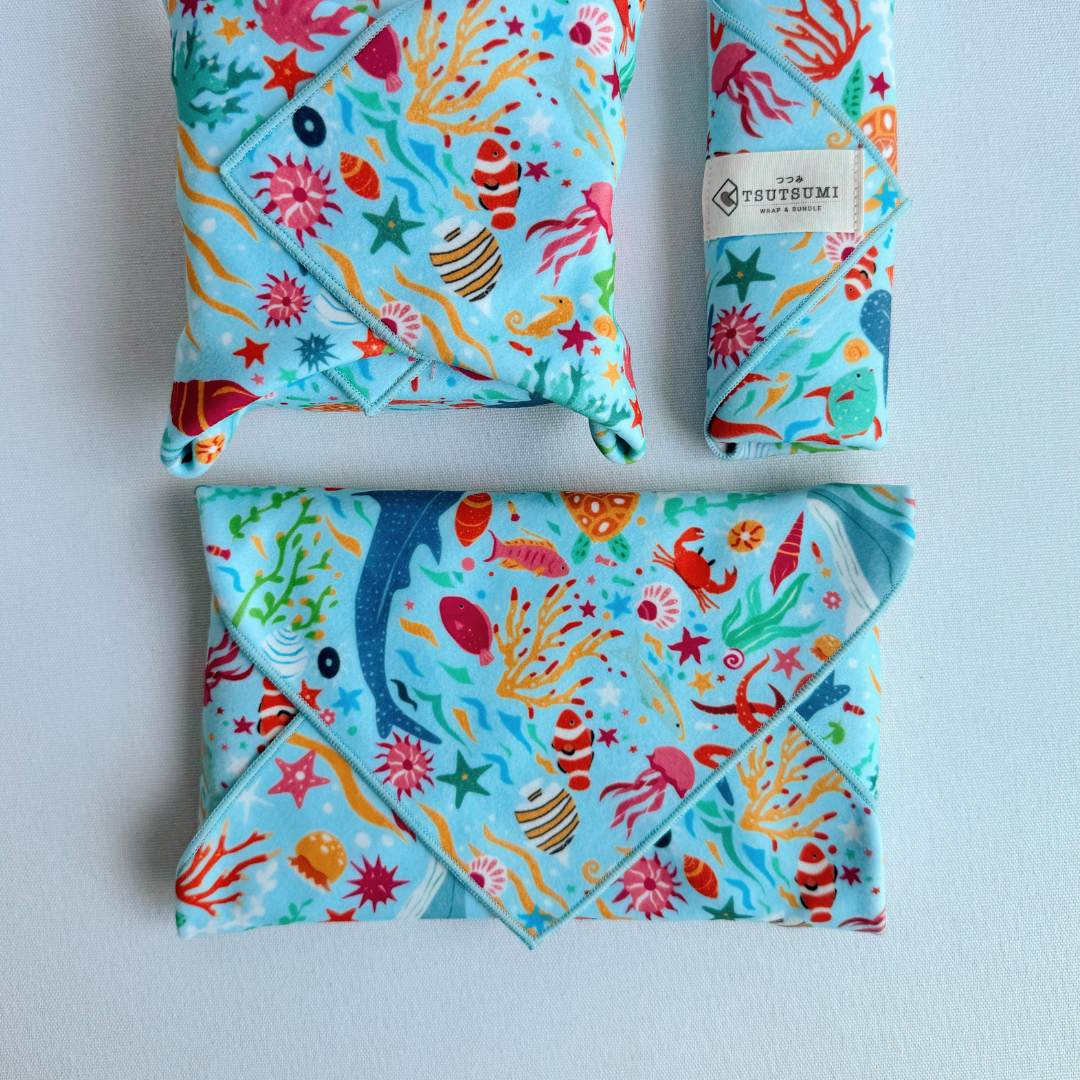 3 packages wrapped with fabric with Marine Fantasy print in light blue background.