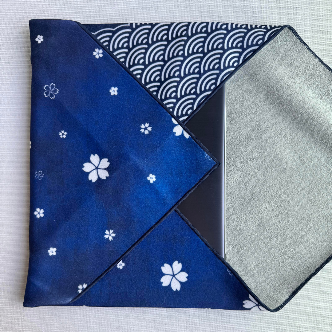 Folded blue fabric with sakura and seigaiha pattern holding a laptop on a white background