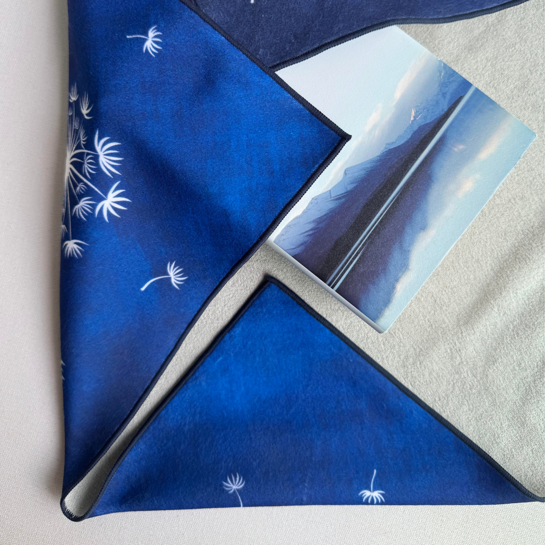 Blue Tanpopo (dandelion) patterned fabric wrap holding a book with a mountain scene on the cover