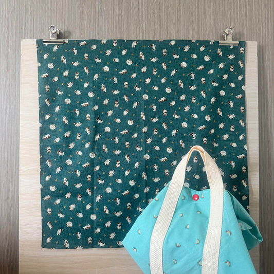 Fabric with Cats and Bells and teal background, and Tsutsumi square wrap used for wrapping a lunchbox