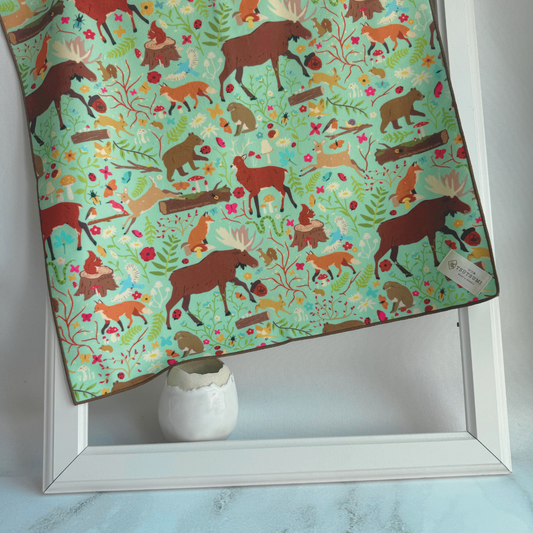 Tsutsumi Clingy Wrap with woodland fantasy artwork on mint green background, draped over a picture frame.