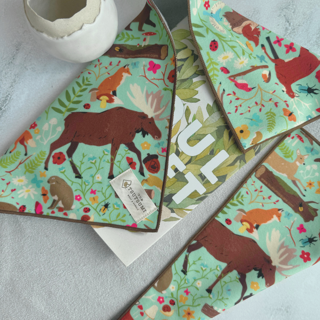 Half opened Tsutsumi Clingy Wrap with woodland creatures artwork on mint green background, used to wrap some books.