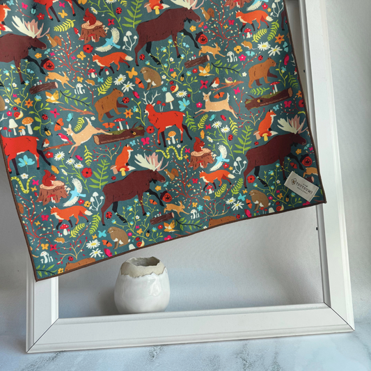 Tsutsumi Clingy Wrap with woodland creatures artwork on dark teal background, draped over a picture frame.