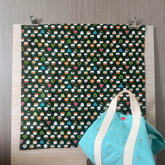 Fabric with Cute Purses icons and green background, and Tsutsumi square wrap used for wrapping a lunchbox