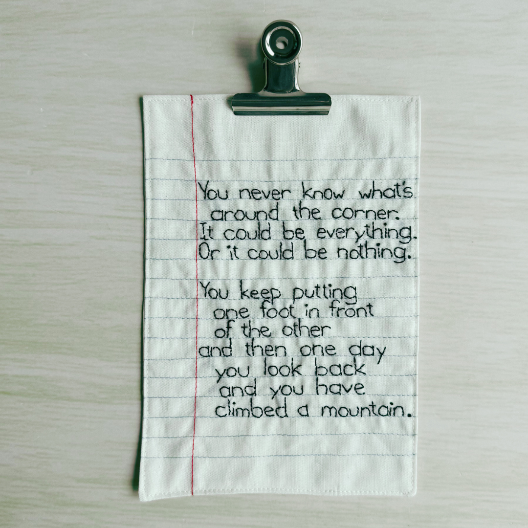 Motivational quote on a piece of lined fabric clipped to a wooden surface