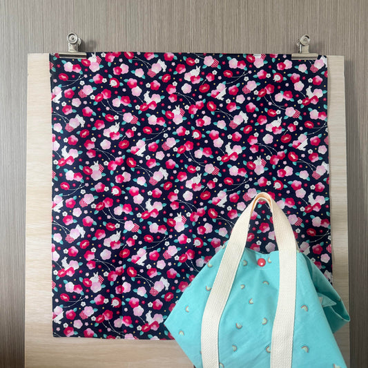 Fabric with Sakura and Rabbits icons and dark blue background, and Tsutsumi square wrap used for wrapping a lunchbox
