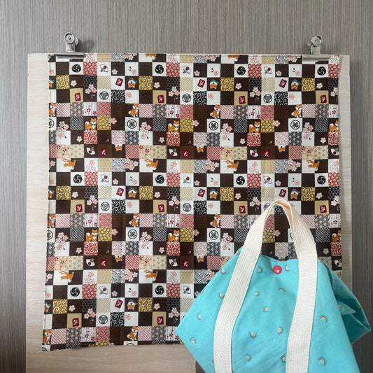 Fabric with Shiba and Japanese icons and brown background, and Tsutsumi square wrap used for wrapping a lunchbox