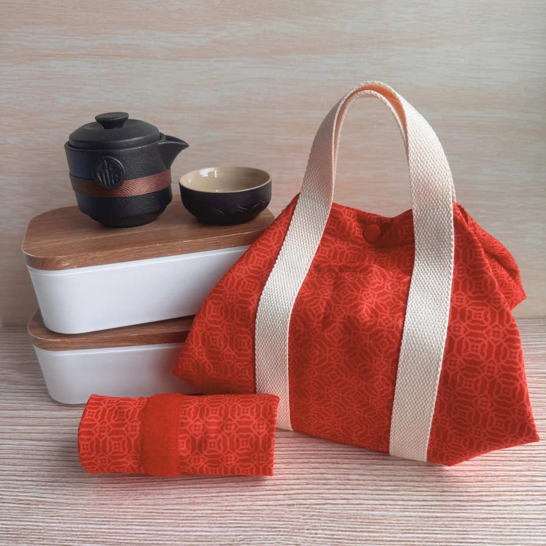 Red patterned fabric carrier with tea set on a wooden surface