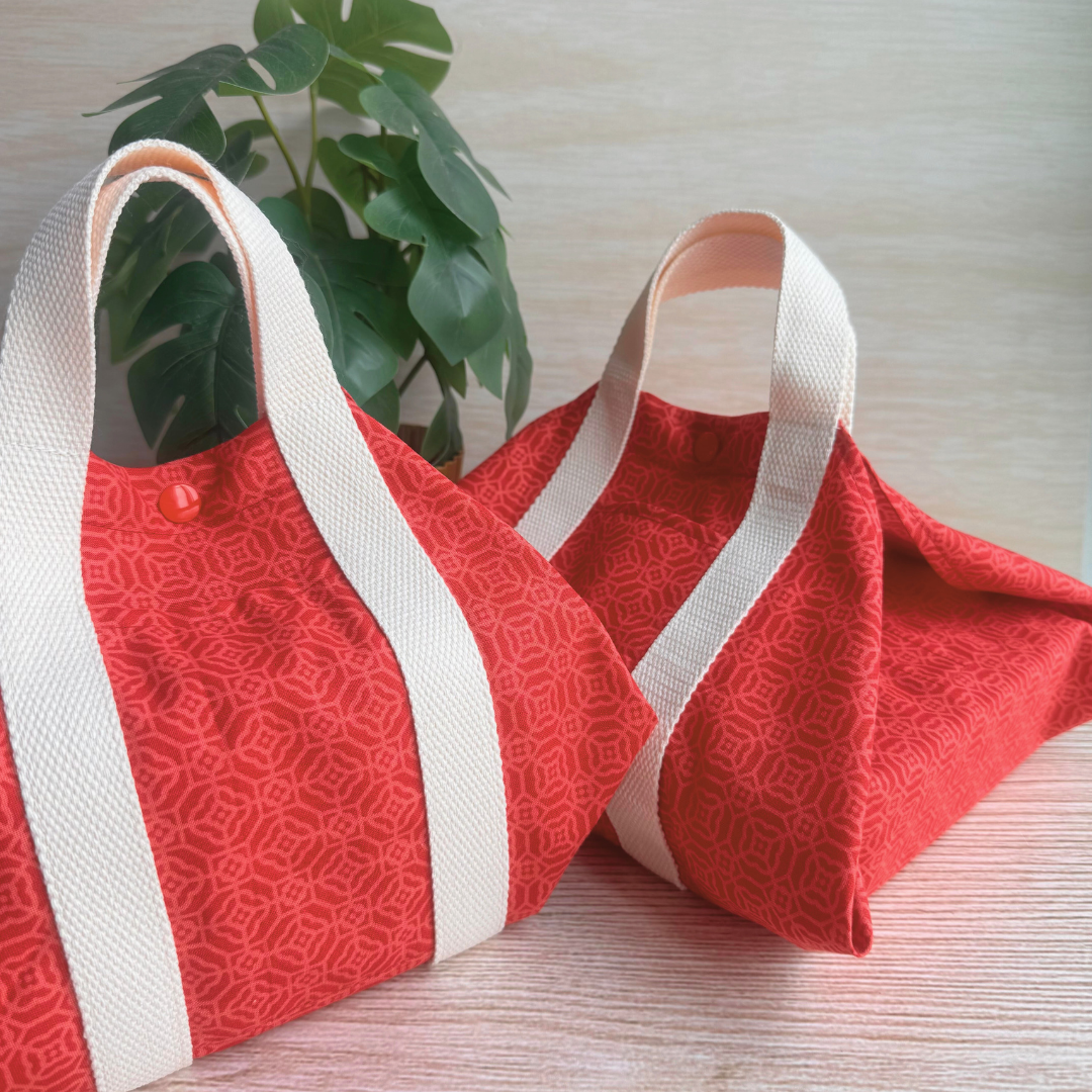 Red fabric bags with white handles on a light wooden surface.