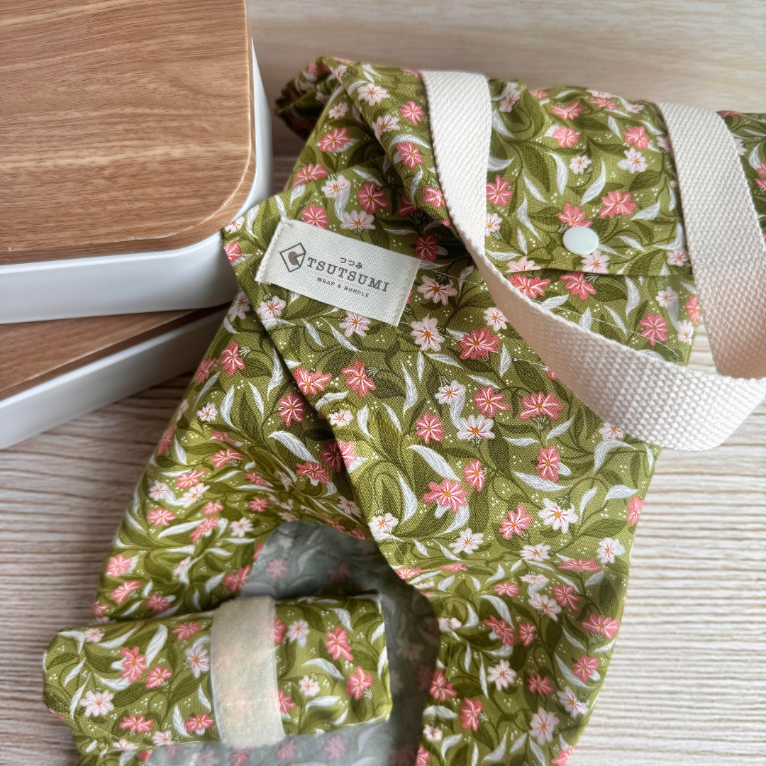 Floral-patterned fabric square wrap with a visible brand label on a wooden surface