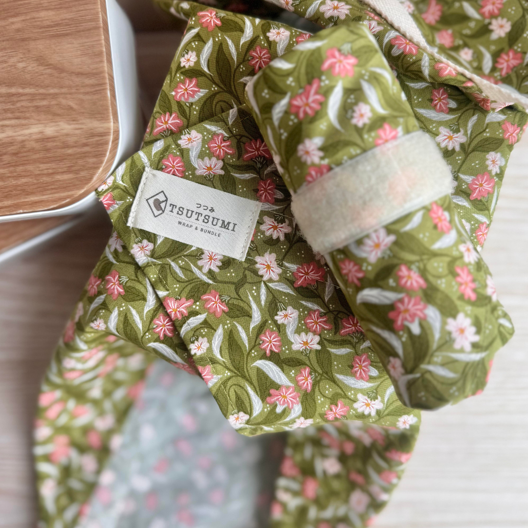 Floral-patterned fabric square wrap with a visible brand label on a wooden surface