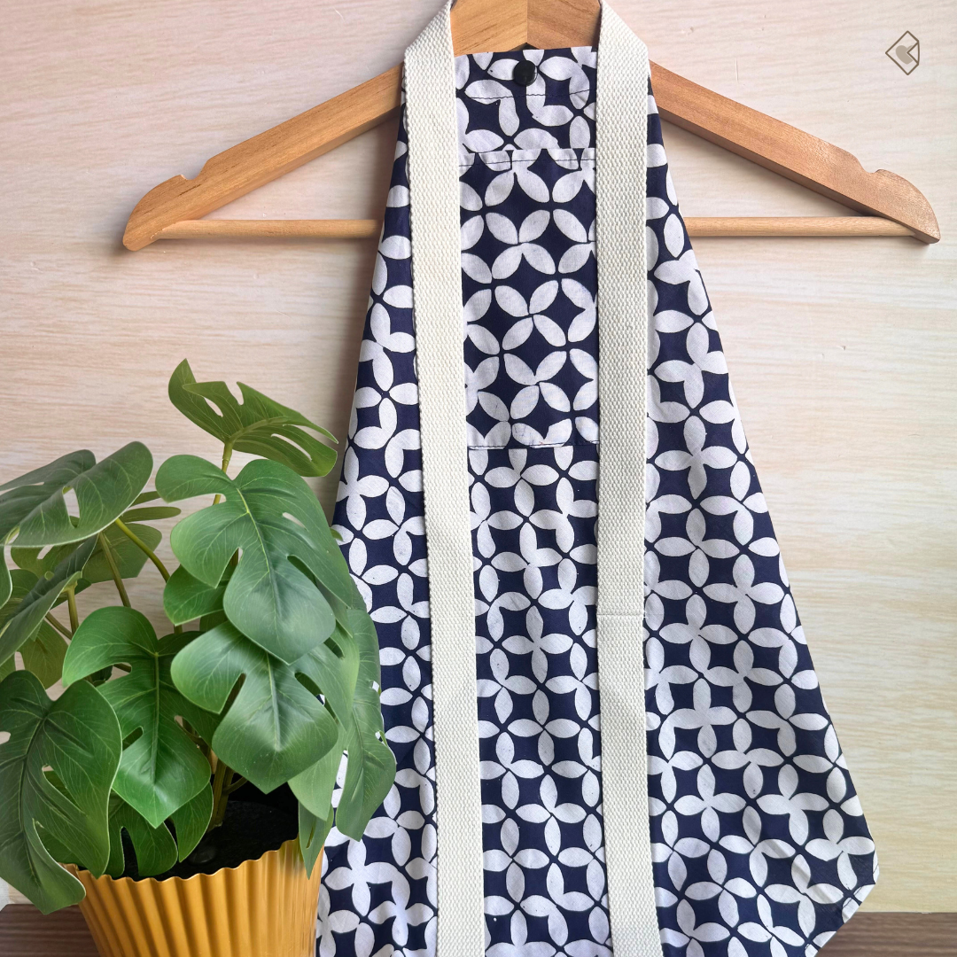Navy blue and white patterned fabric wrap on a wooden hanger with a plant in the background