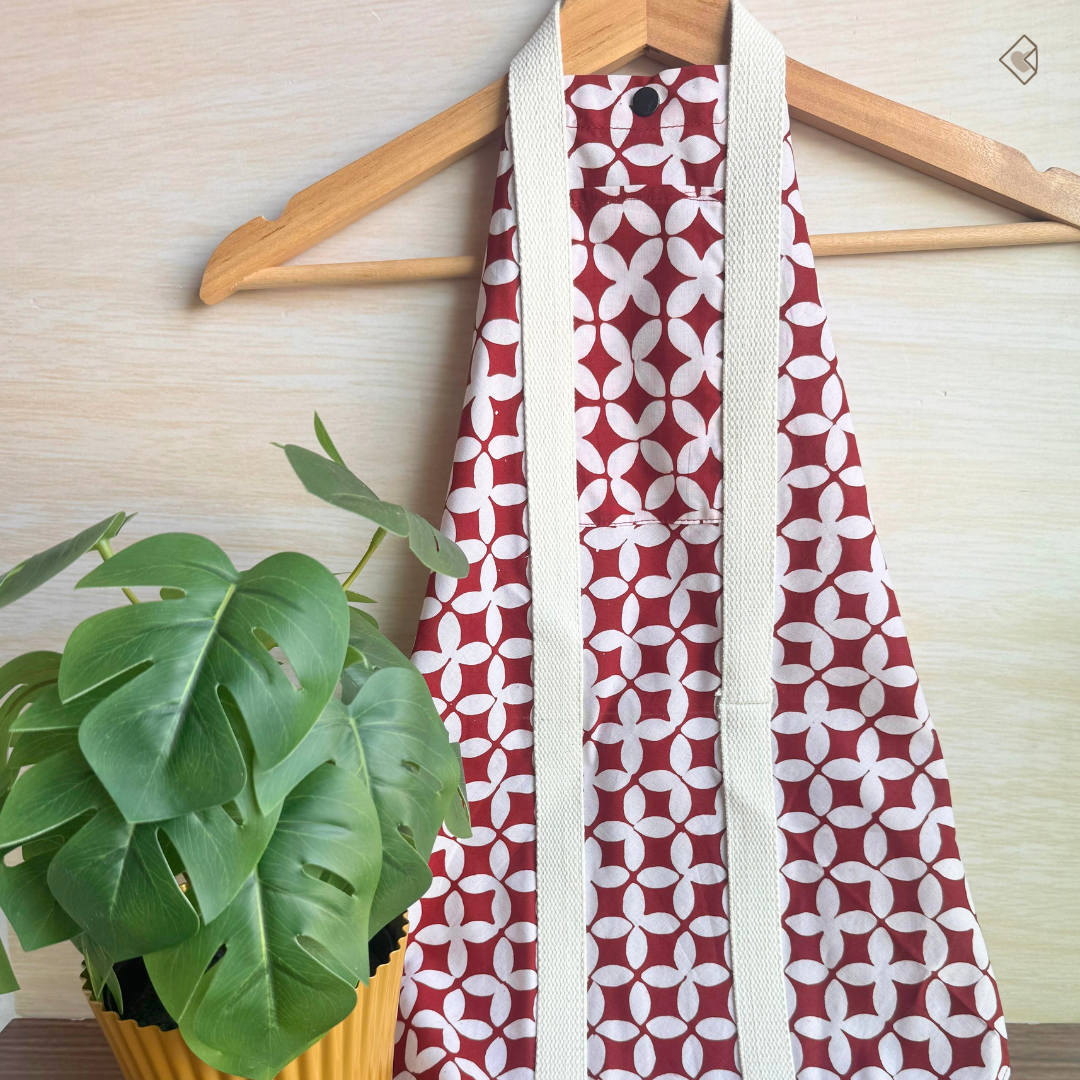 Red and white patterned fabric wrap on a wooden hanger with a plant in the background