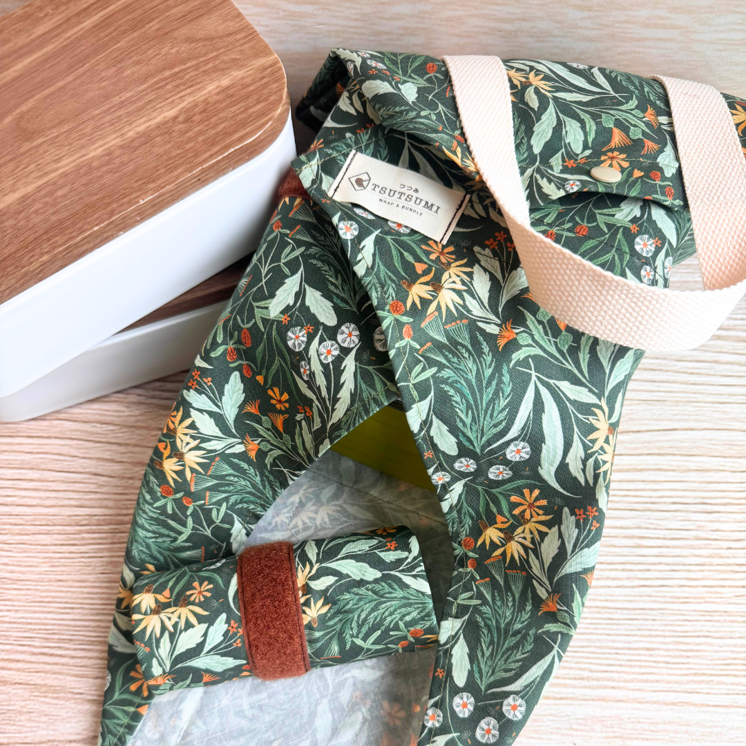 Green floral-patterned square wrap holding a green box next to 2 lunchboxes