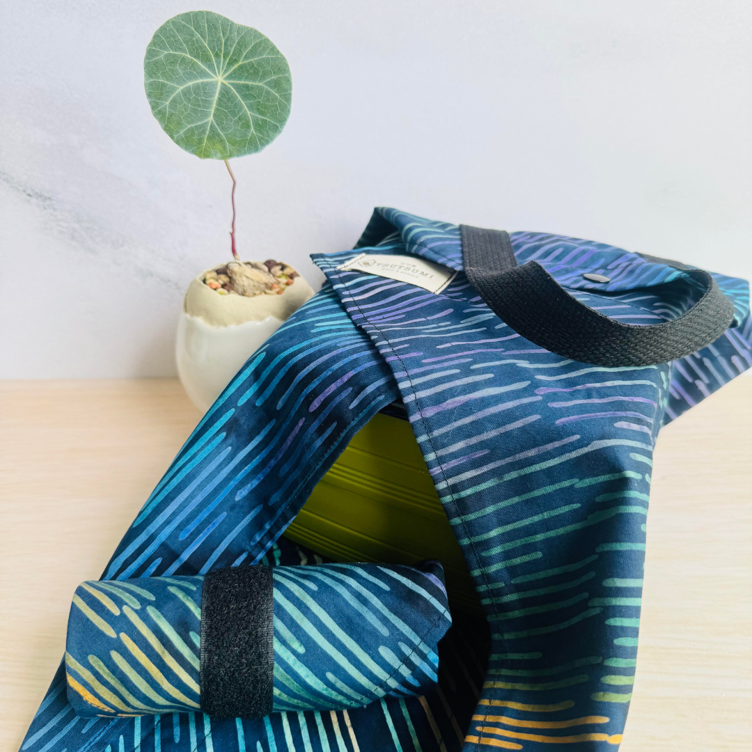 Half opened Navy fabric Square Wrap holding a green lunch box, and a rolled up Navy fabric Square Wrap