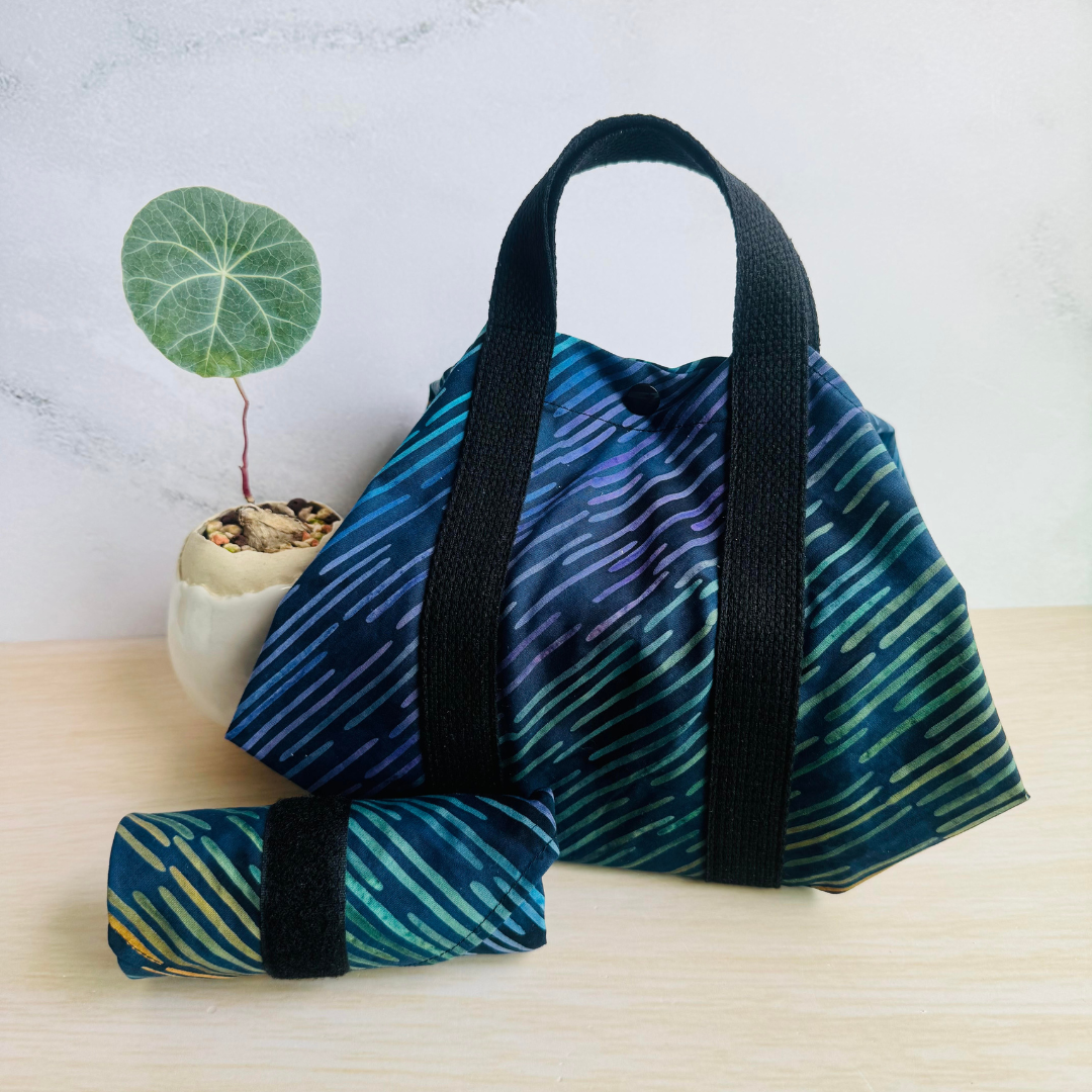 Navy Square Wrap with black straps,  with a small plant in the background.